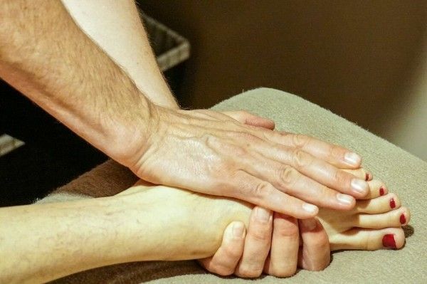 Hands giving a foot massage on a towel-covered surface.