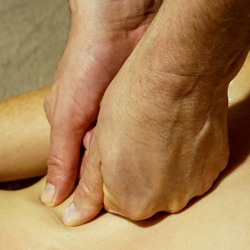 Hands performing deep tissue massage on a person's back