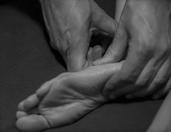 Hands holding and massaging a person's wrist and palm in a black-and-white close-up.