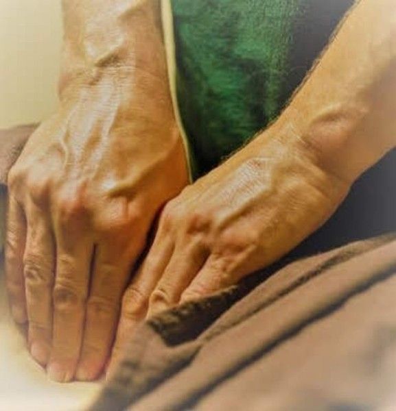 Hands pressing and smoothing brown fabric on a sewing work surface