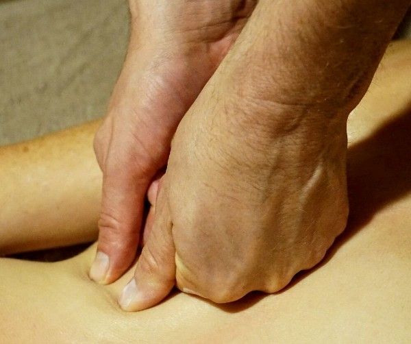 Hands pressing into a bare back during a massage