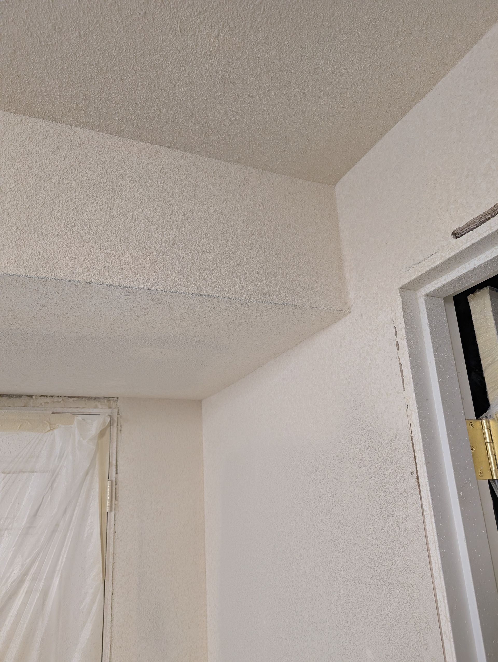 Interior corner of a room with white walls, textured ceiling, and a doorway on the right.