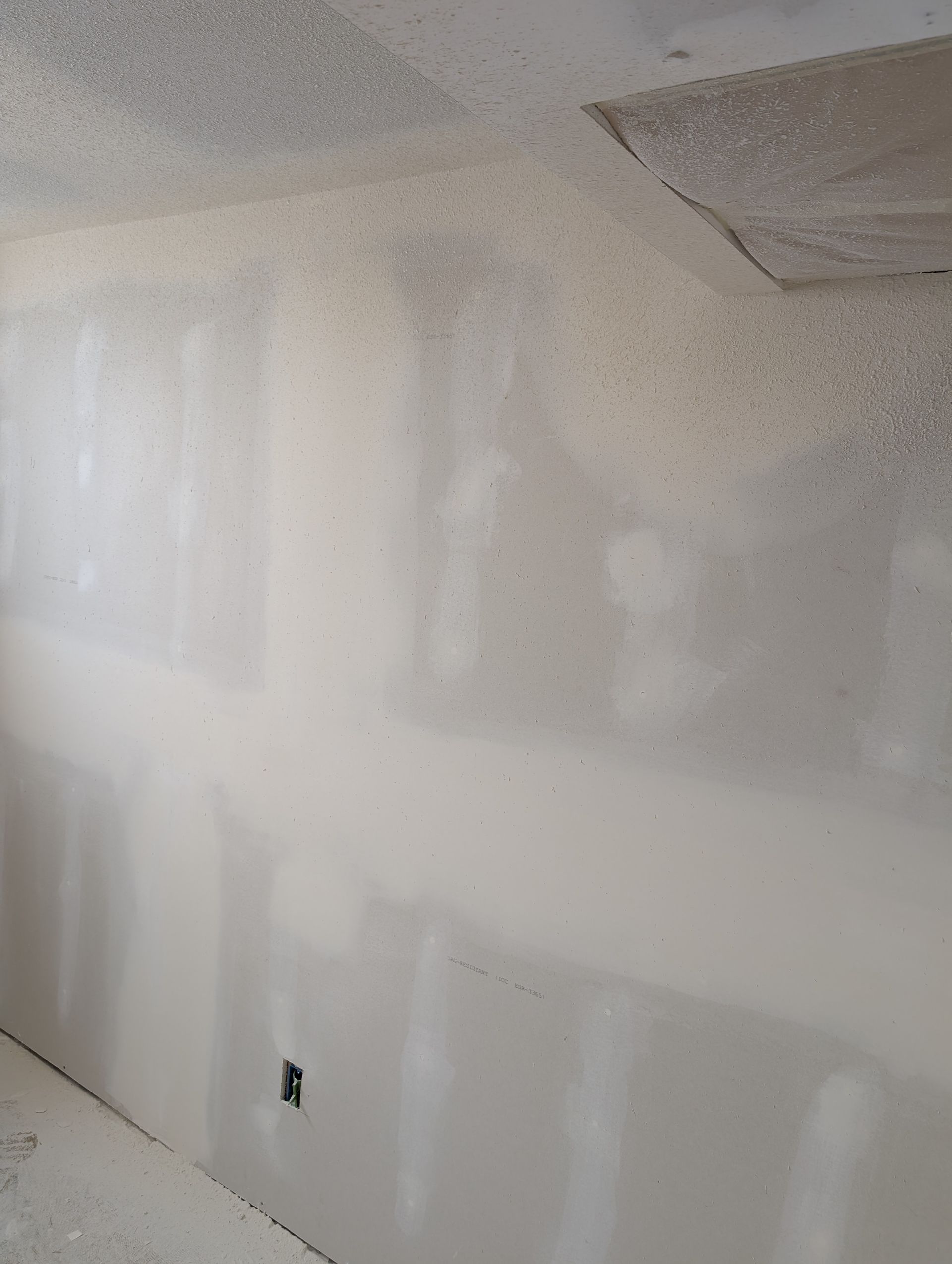 Unfinished drywall wall and ceiling with taped seams in a room under renovation.