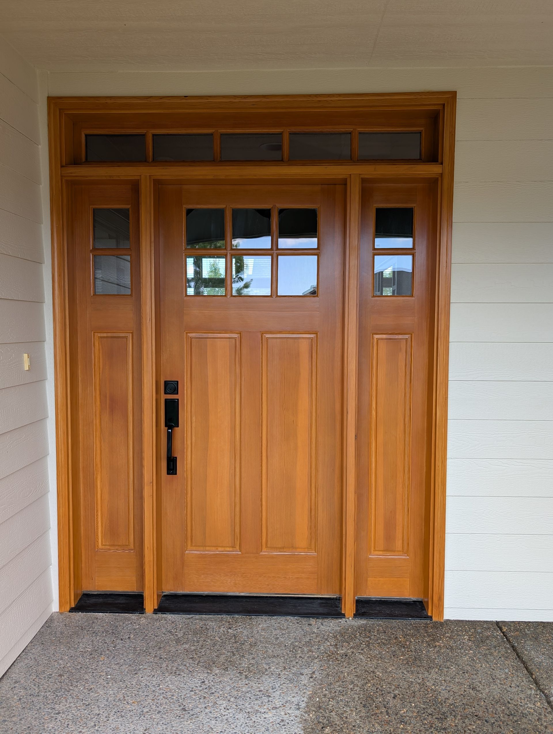Wooden front door with sidelights and small window panes in a beige exterior wall