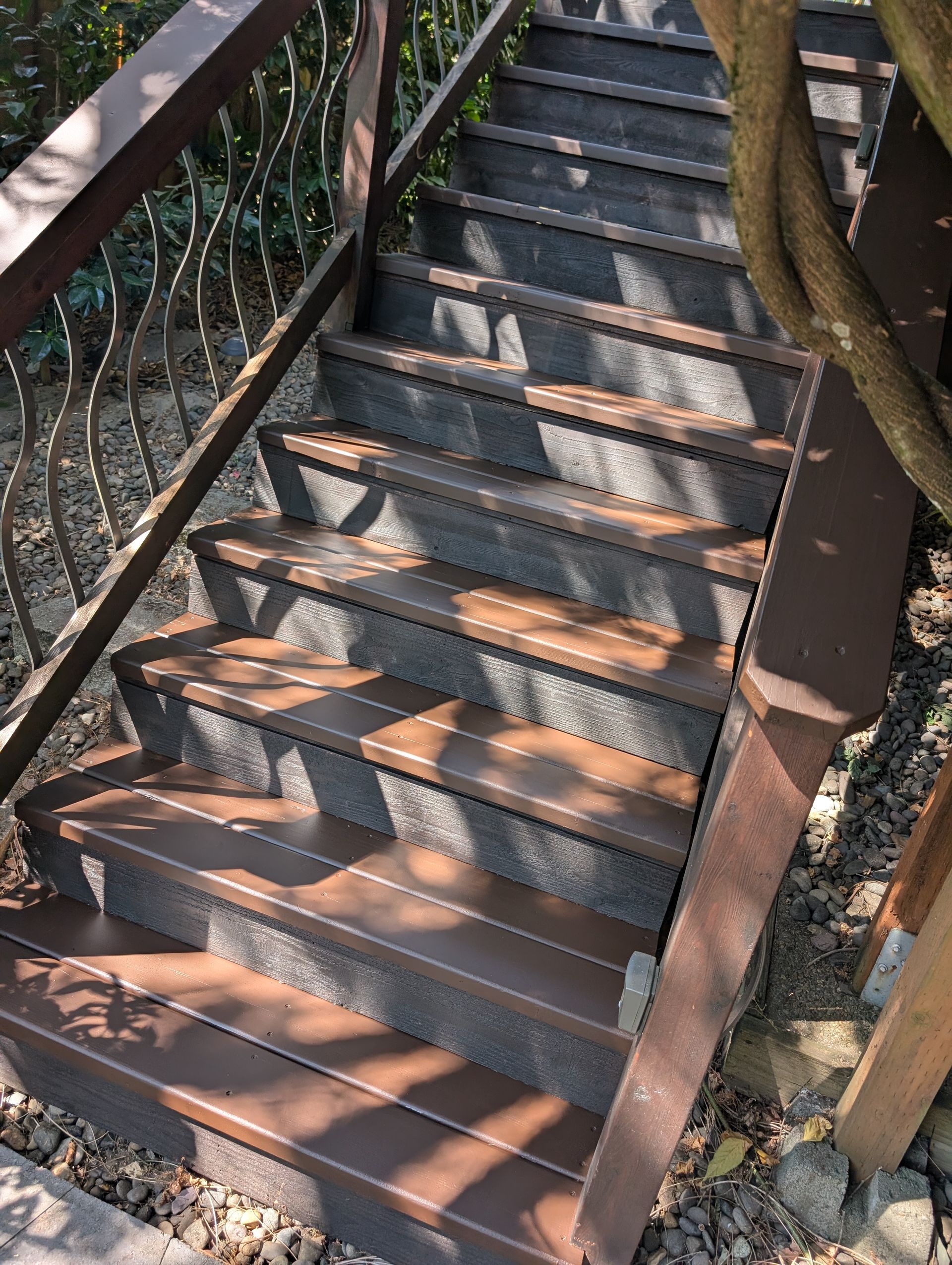 Outdoor metal staircase with sunlight and shadow patterns on the steps and railings