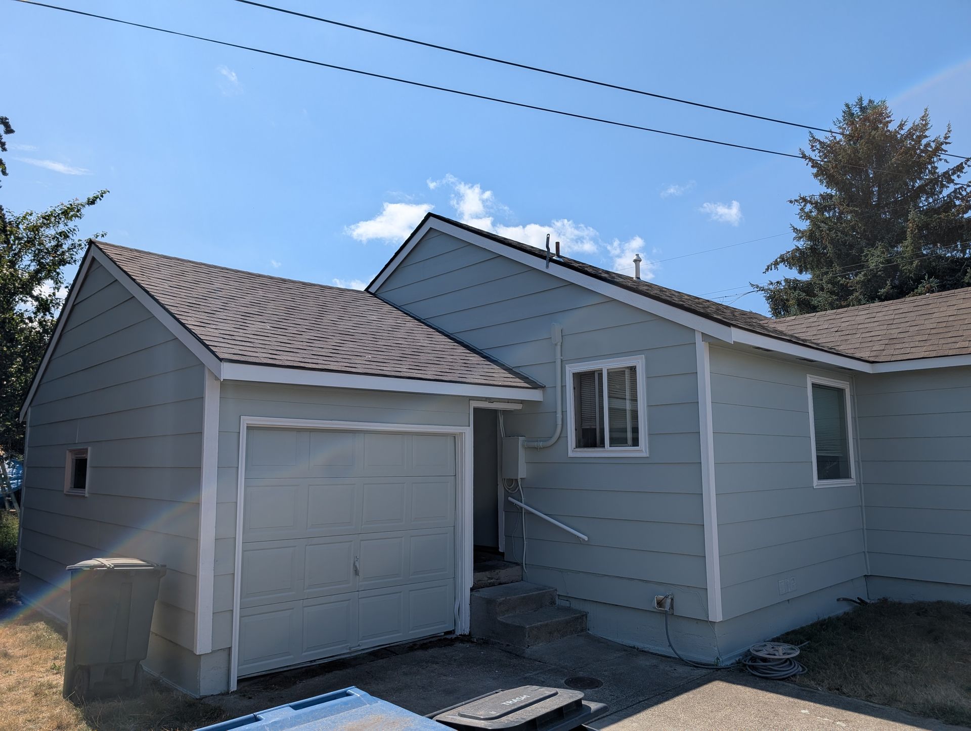 Small gray house with attached garage and blue sky overhead