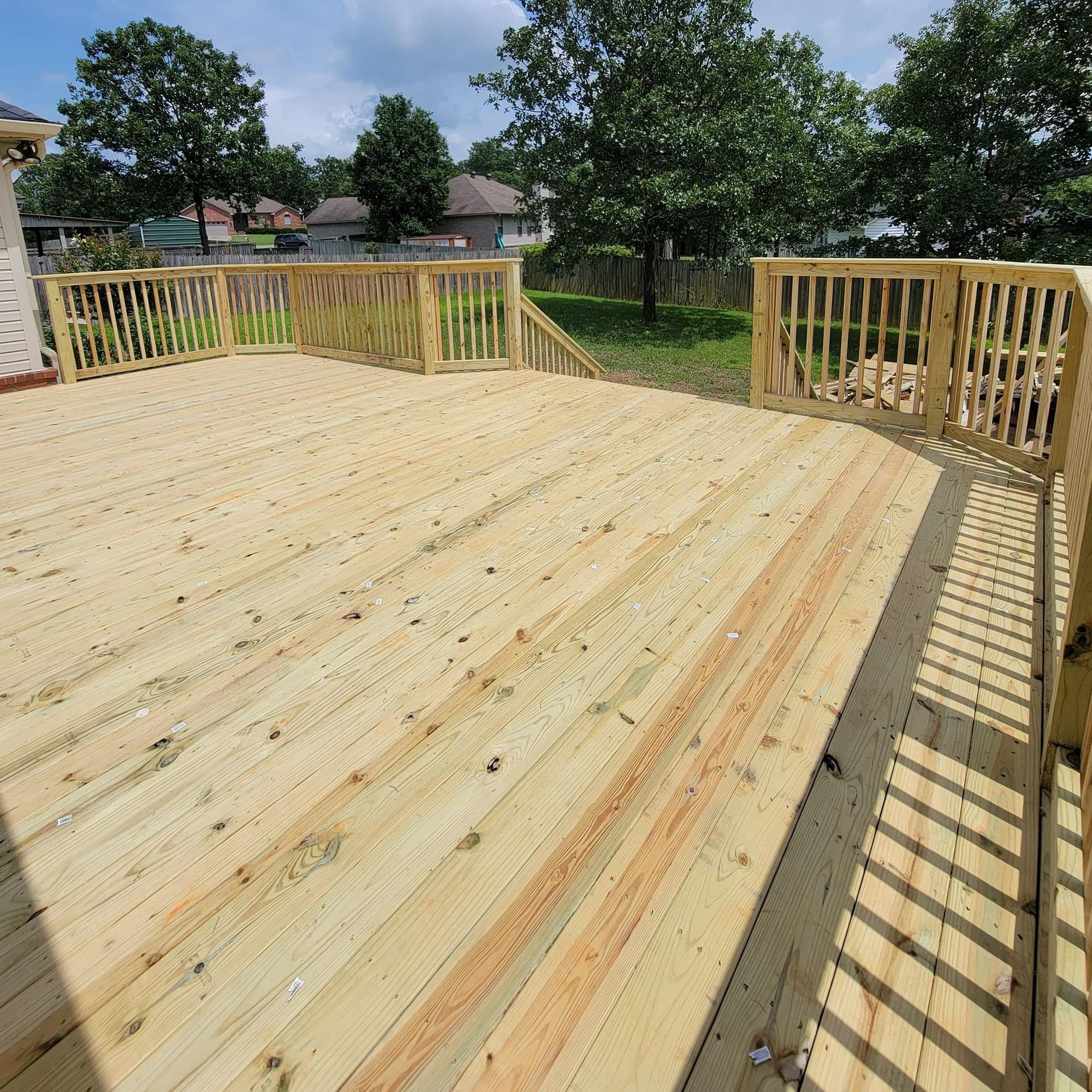 New wooden deck under construction with railings in a sunny backyard