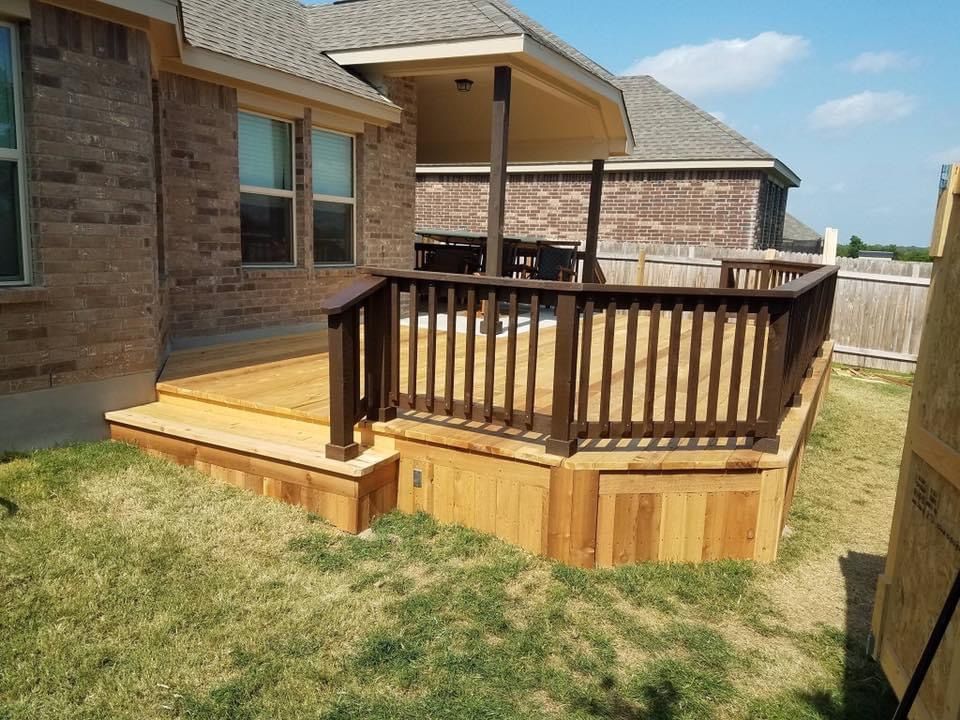 Back patio deck with wooden railings and steps beside a brick house, overlooking a grassy yard