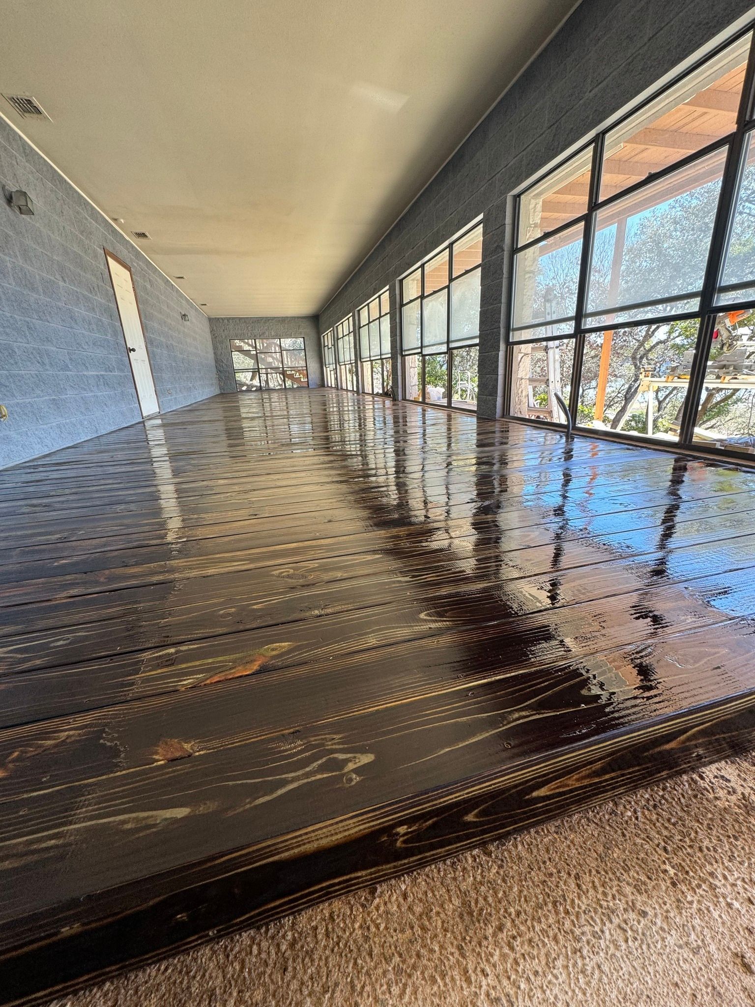 Empty indoor hallway with glossy dark floor and large windows on the right