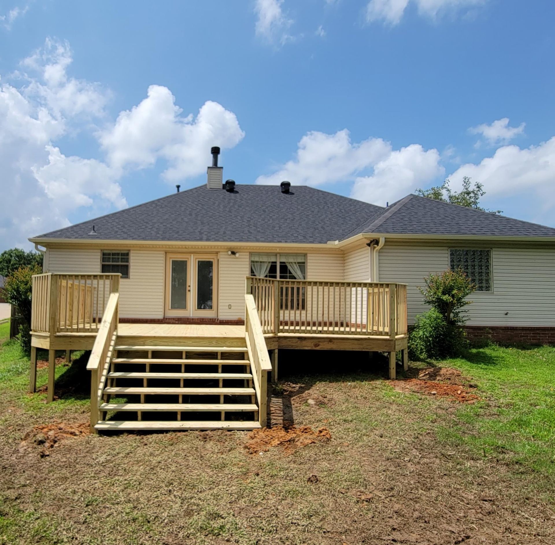 Back deck with stairs on a beige house under a blue sky