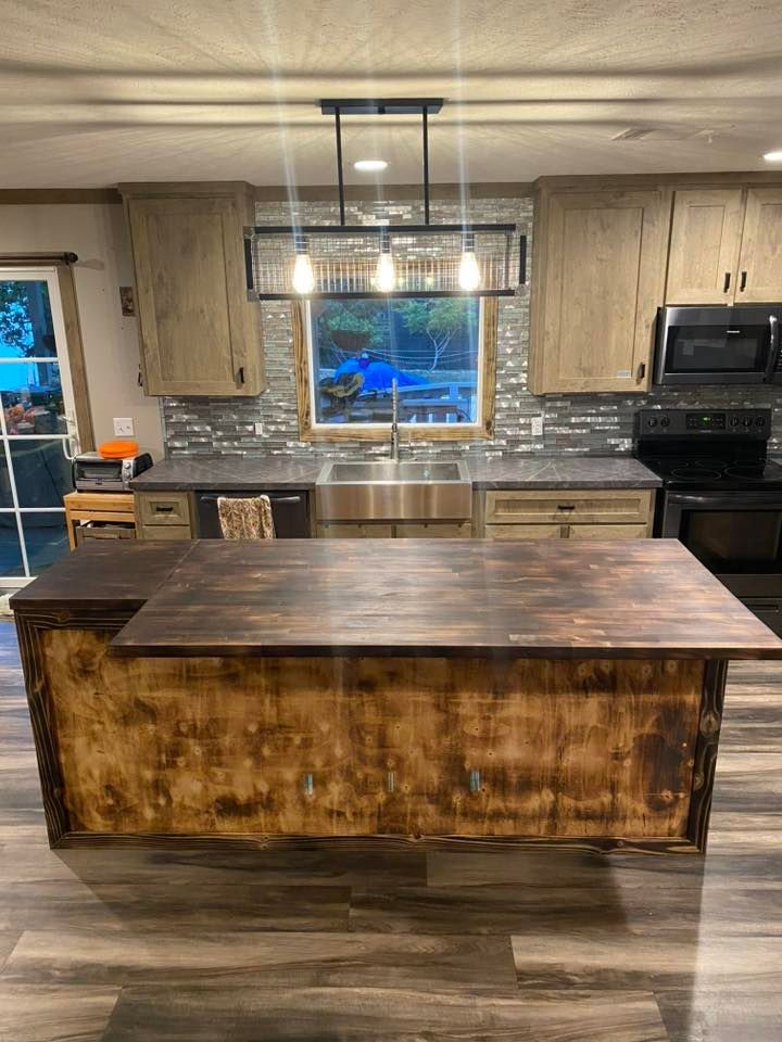 Modern kitchen with a large rustic wooden island, stainless sink, and pendant lights over the counter.