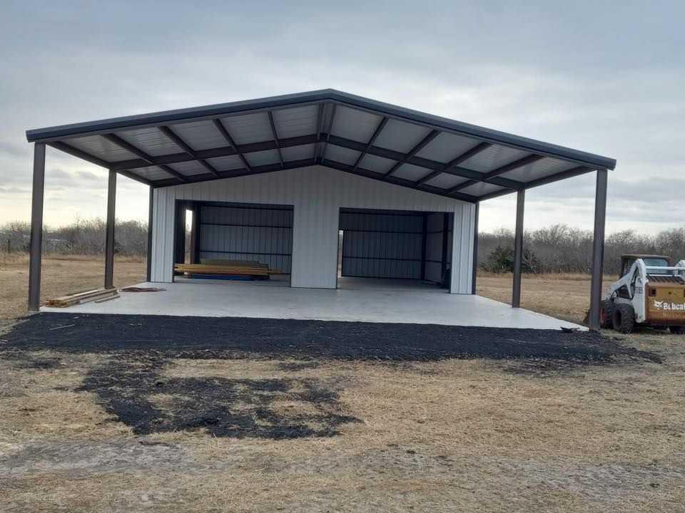 Large metal carport with concrete slab and open bays in a rural dirt lot