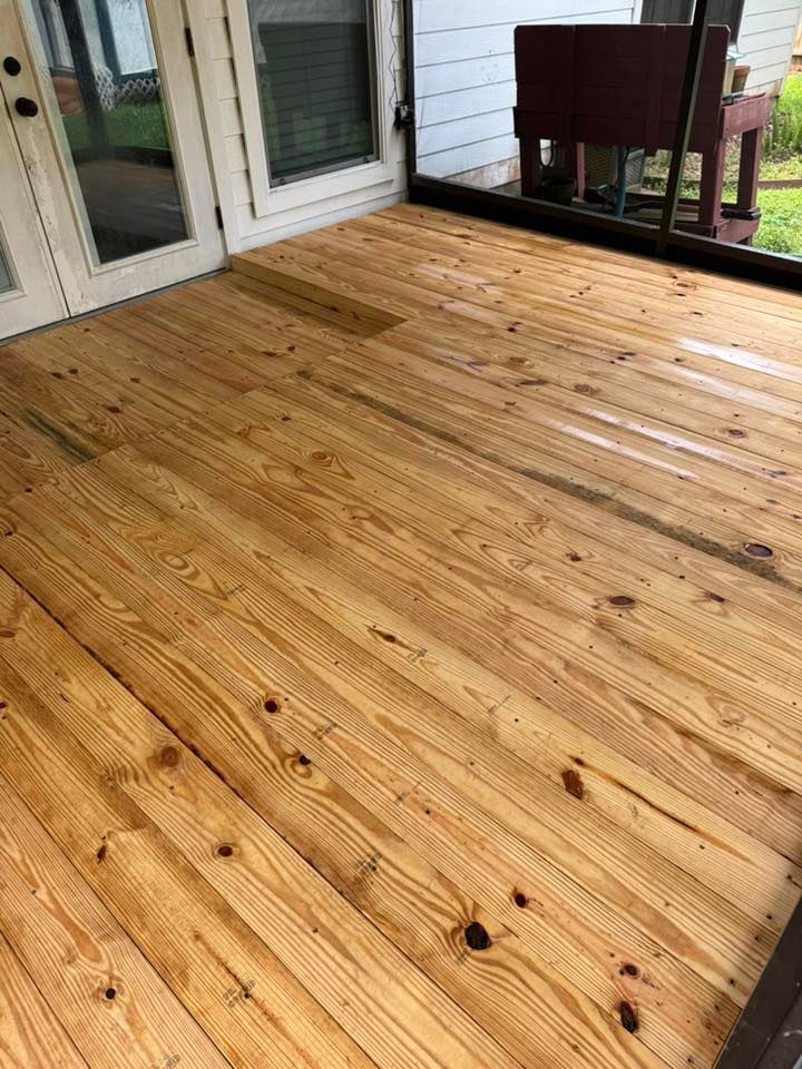 Wooden deck with fresh honey-colored boards beside white patio doors and a railing.