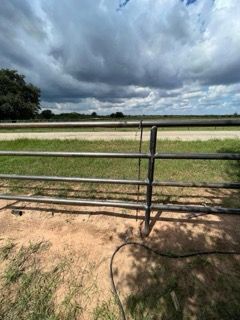 Metal fence beside a grassy field under dramatic cloudy sky