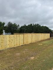 Fresh wooden fence along a grassy field under a cloudy sky