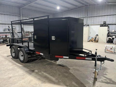 Black enclosed utility trailer with tandem axles parked inside a workshop.