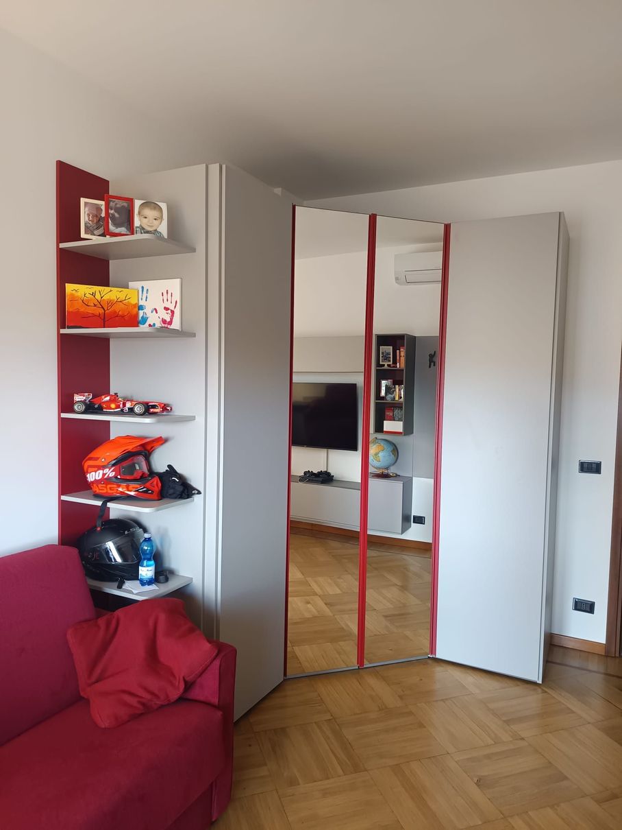 Soggiorno moderno con divano componibile bianco, pavimenti in legno e ampia finestra.