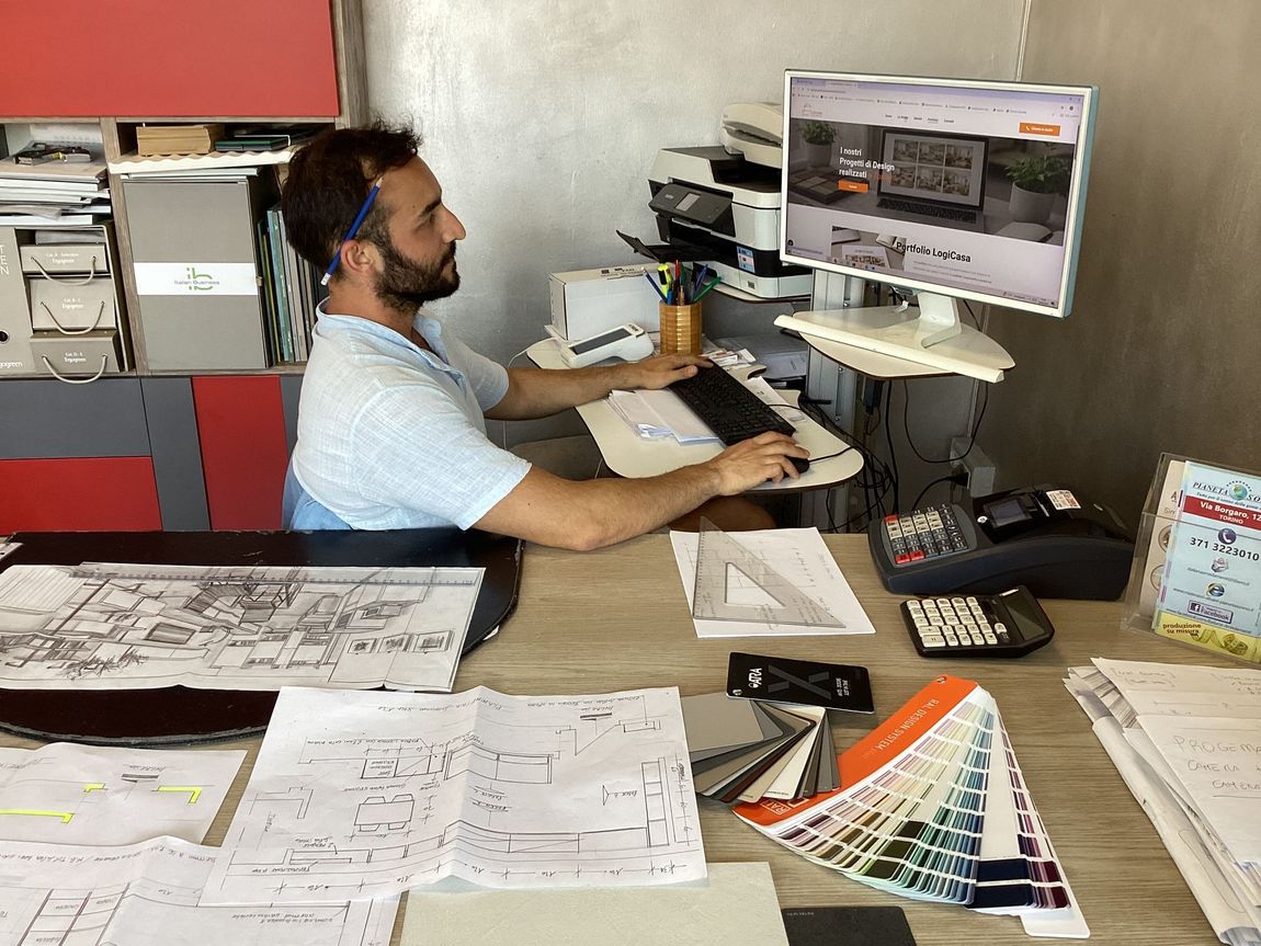 Persone in un ufficio che esaminano i progetti; una donna mostra il rendering di una stanza su un tablet.
