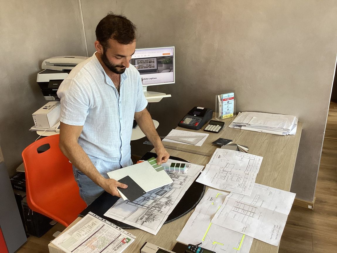 Persone che esaminano progetti architettonici, campioni di colori e campioni di ante di armadi su una scrivania.