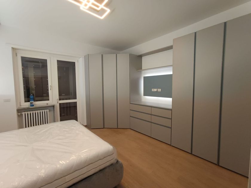 Soggiorno moderno con divano componibile bianco, pavimenti in legno e ampia finestra.