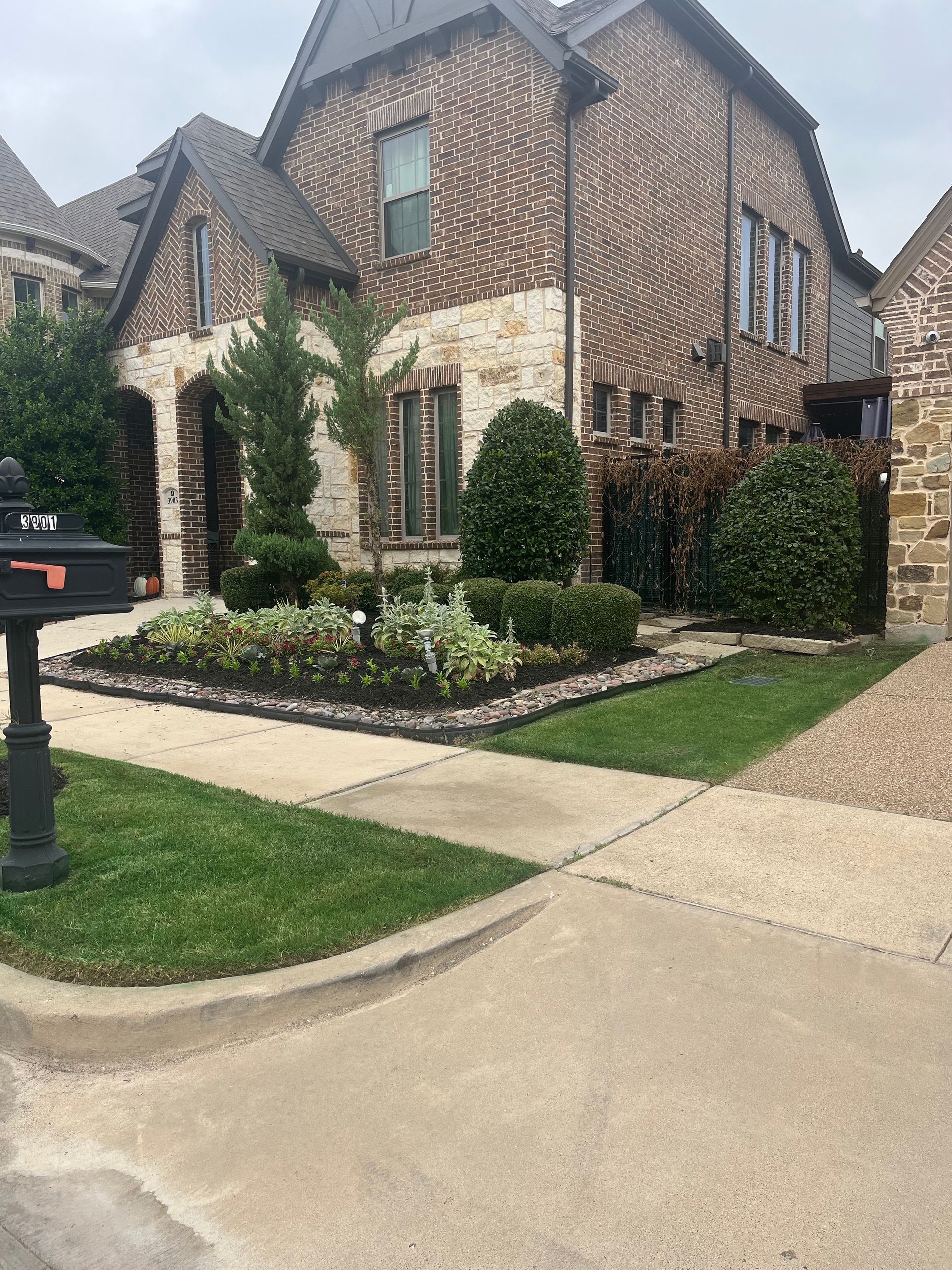 Brick suburban house with ivy, manicured lawn, and driveway on a quiet street