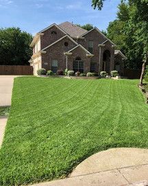 Brick suburban house with a wide, neatly mowed green lawn and driveway in front
