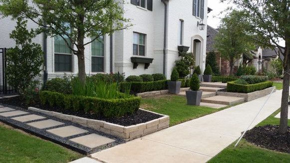 Apartment walkway with landscaped hedges, trees, and a white building exterior
