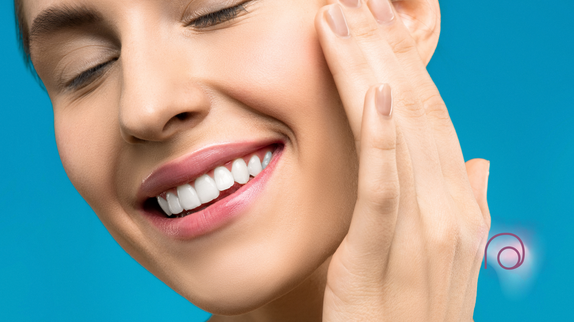 A woman is smiling and touching her face with her hand.
