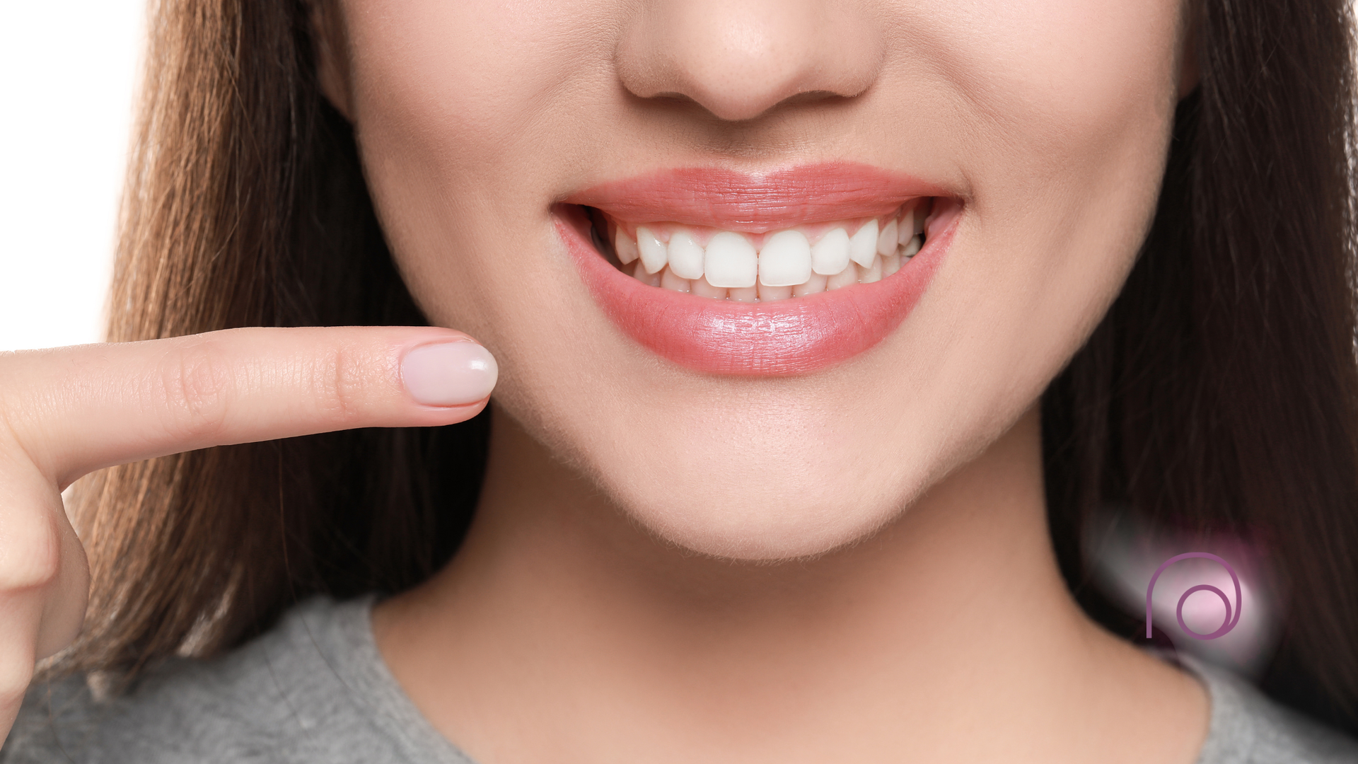 A woman is pointing at her teeth with her finger.