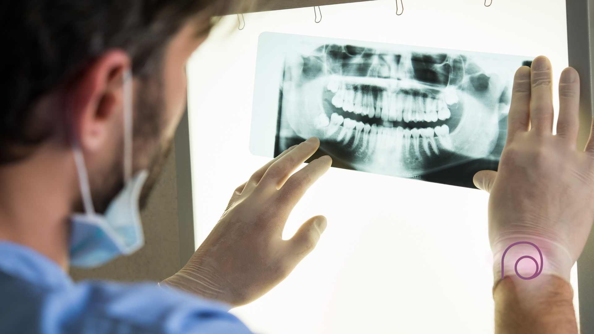 A dentist is looking at an x-ray of a person 's teeth.
