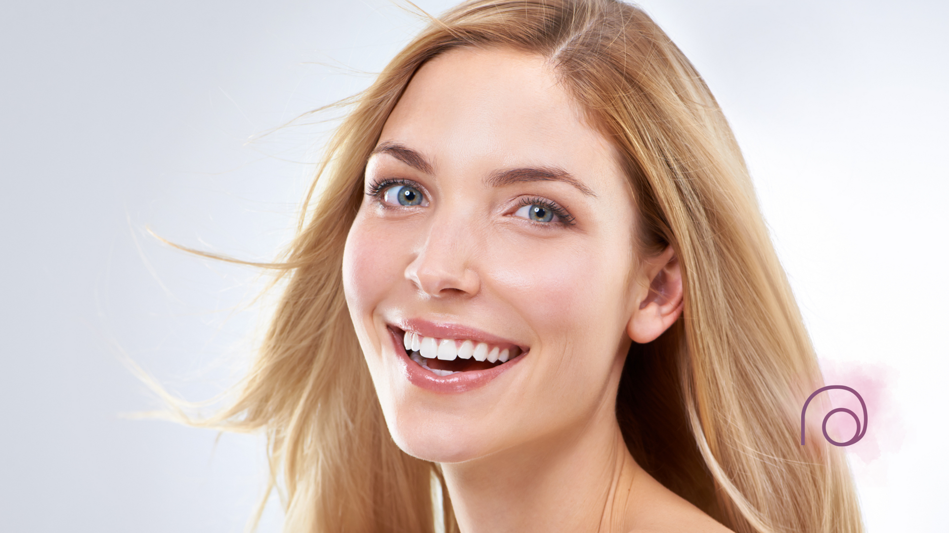 A woman with long blonde hair is smiling and looking at the camera.
