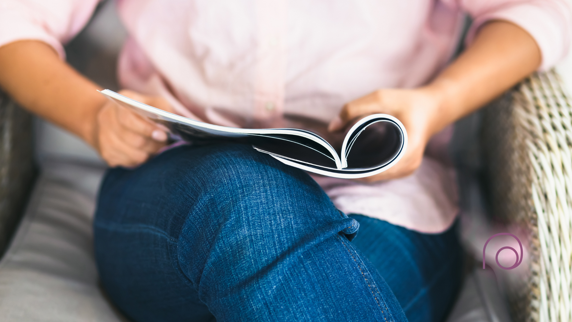 A woman is sitting in a chair reading a magazine.