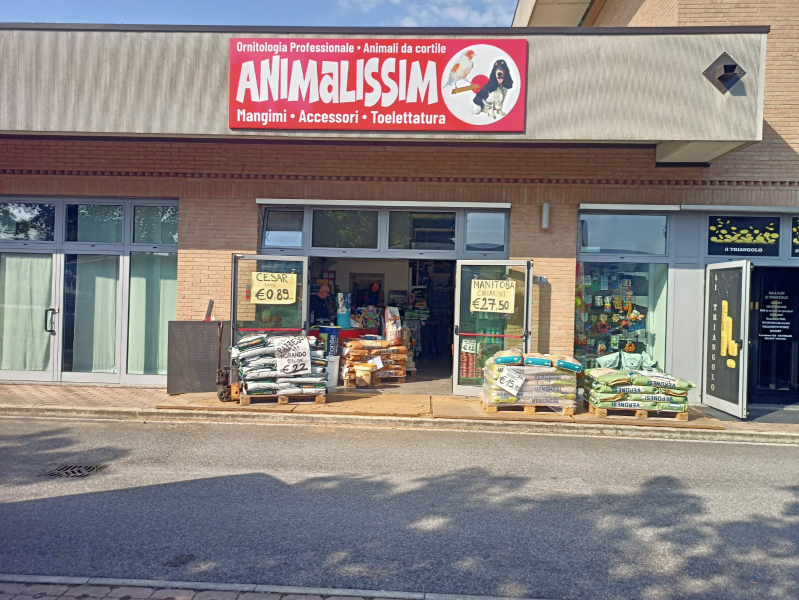 Negozio di articoli per animali con insegna rossa e scaffali di cibo per animali all'ingresso.