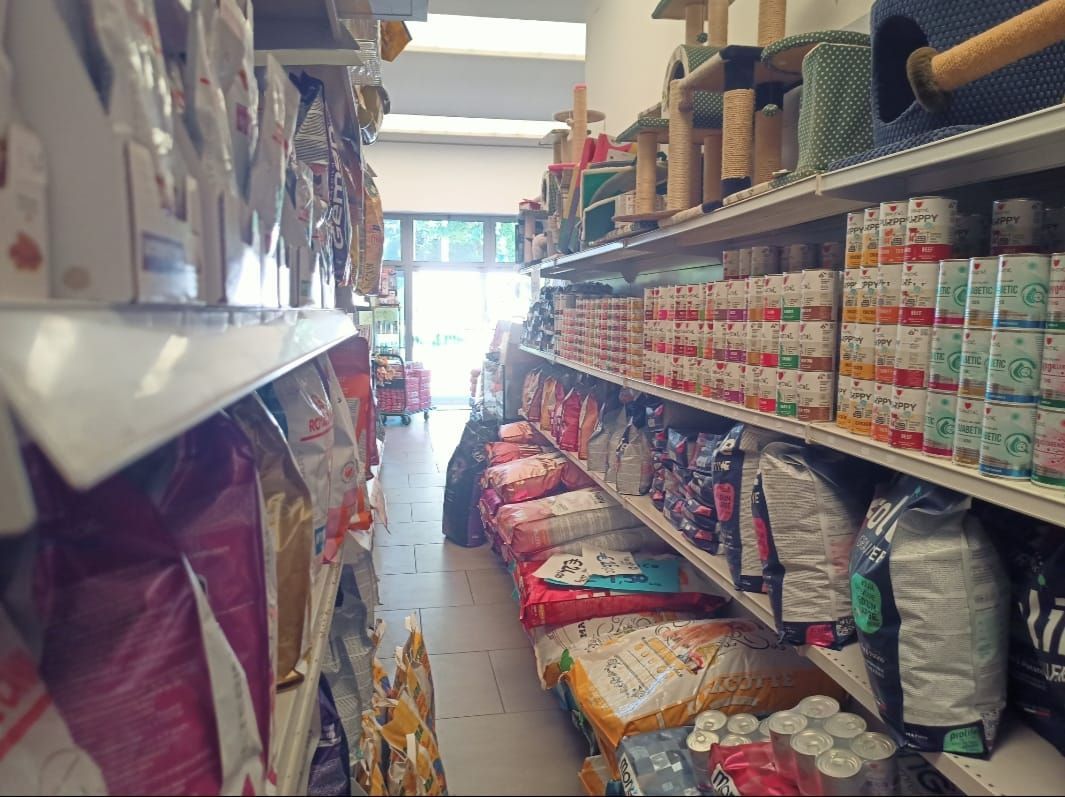 Un corridoio di un supermercato con scaffali pieni di prodotti confezionati e lattine colorate, ben illuminato vicino all'ingresso.