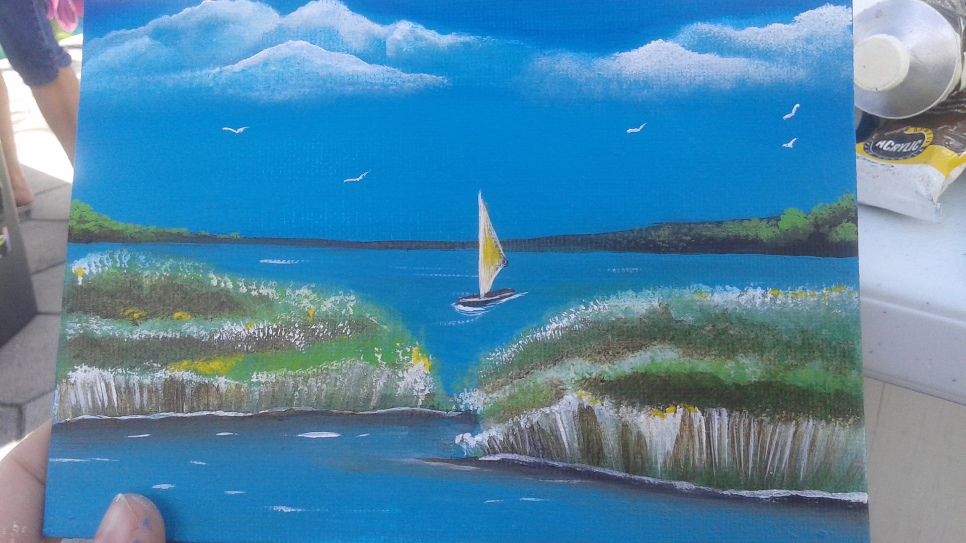 A person is holding a painting of a sailboat in the ocean.