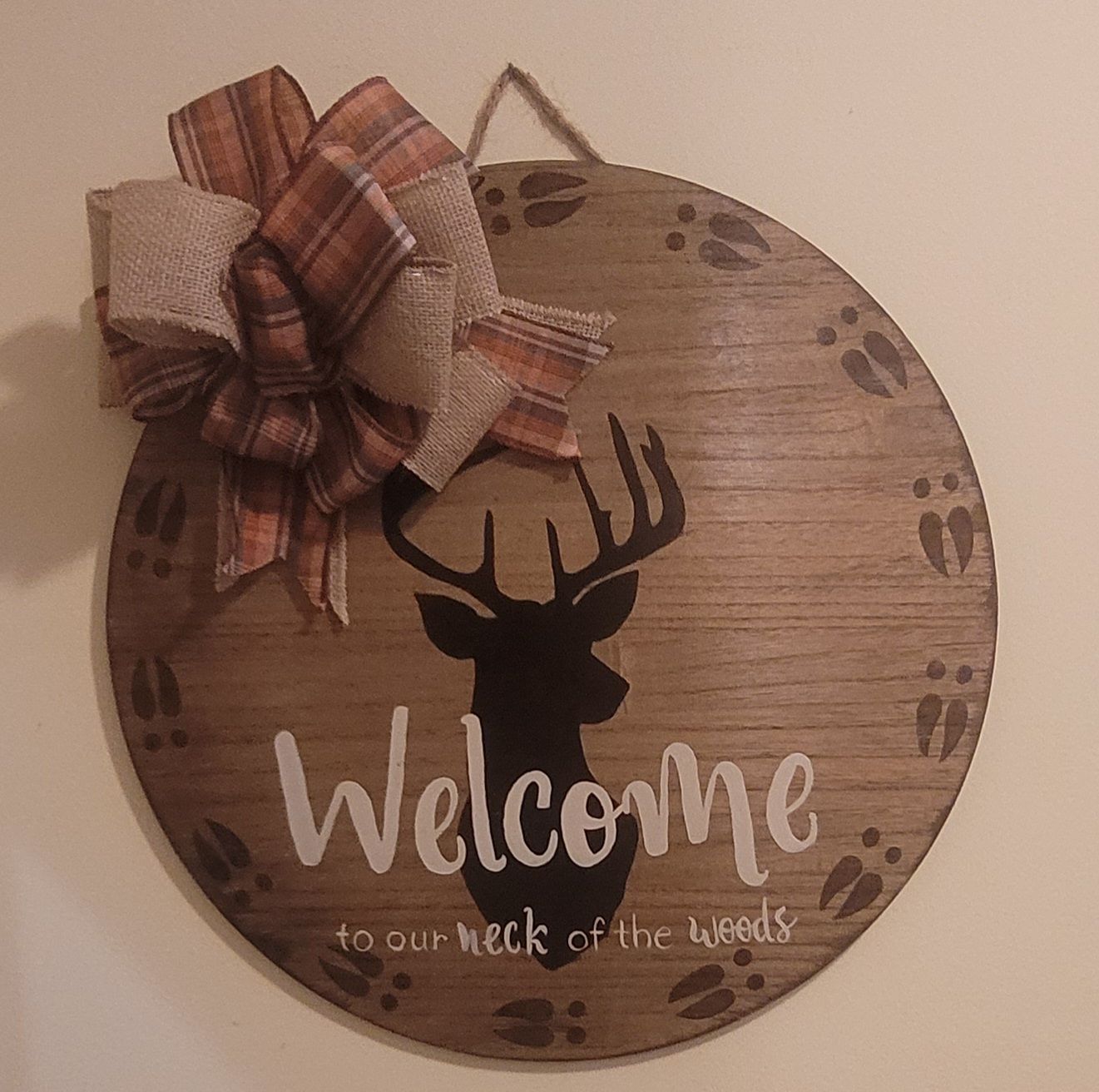 A wooden sign with a deer and the words welcome to our neck of the woods