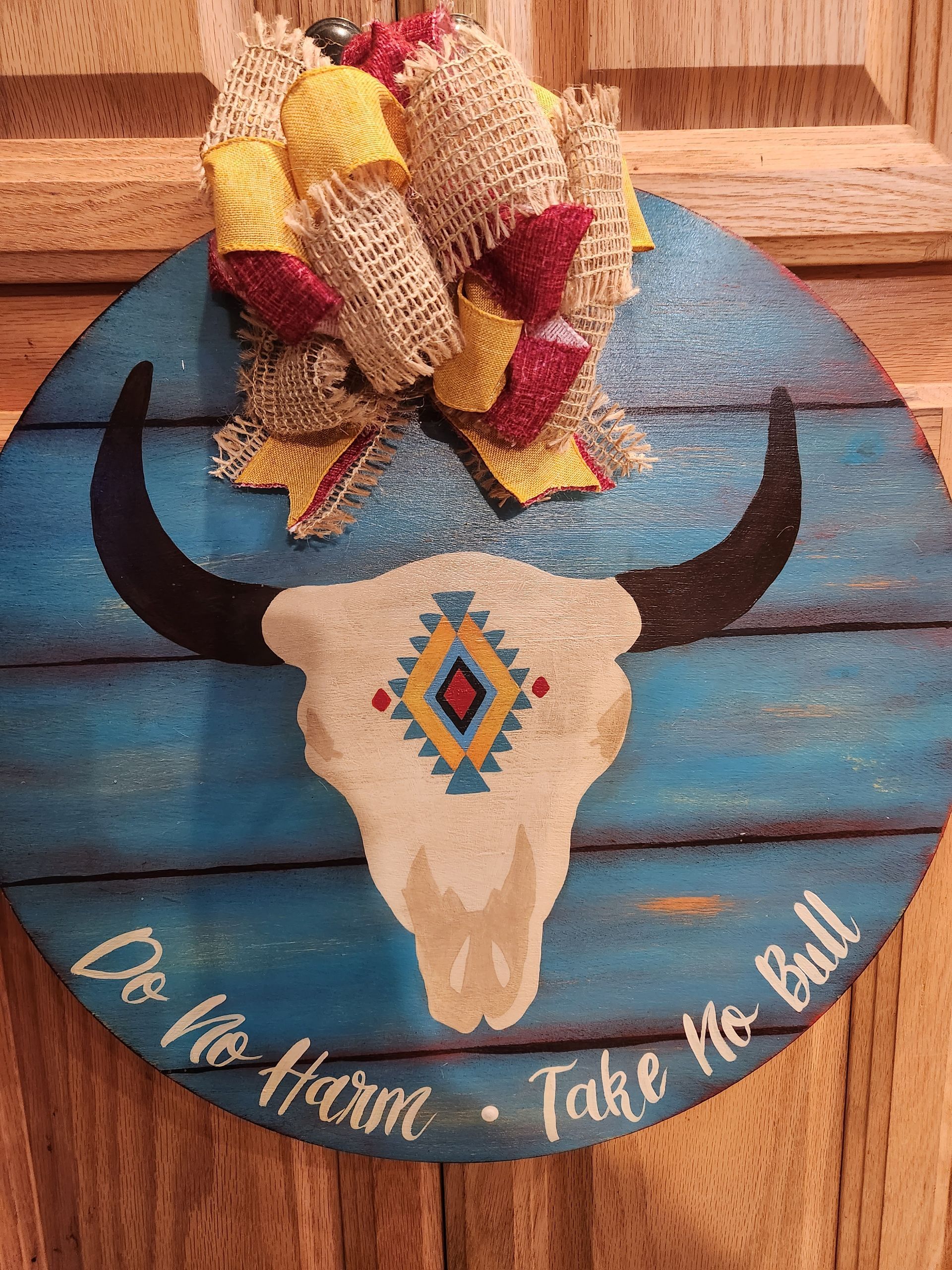 A wooden sign with a bull skull painted on it.