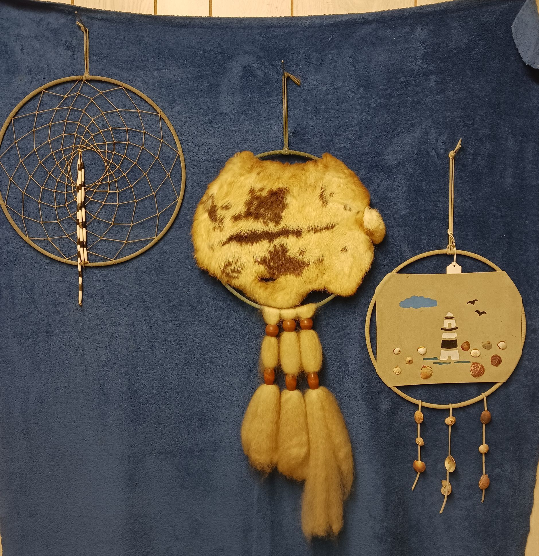 Three dream catchers are hanging on a blue blanket