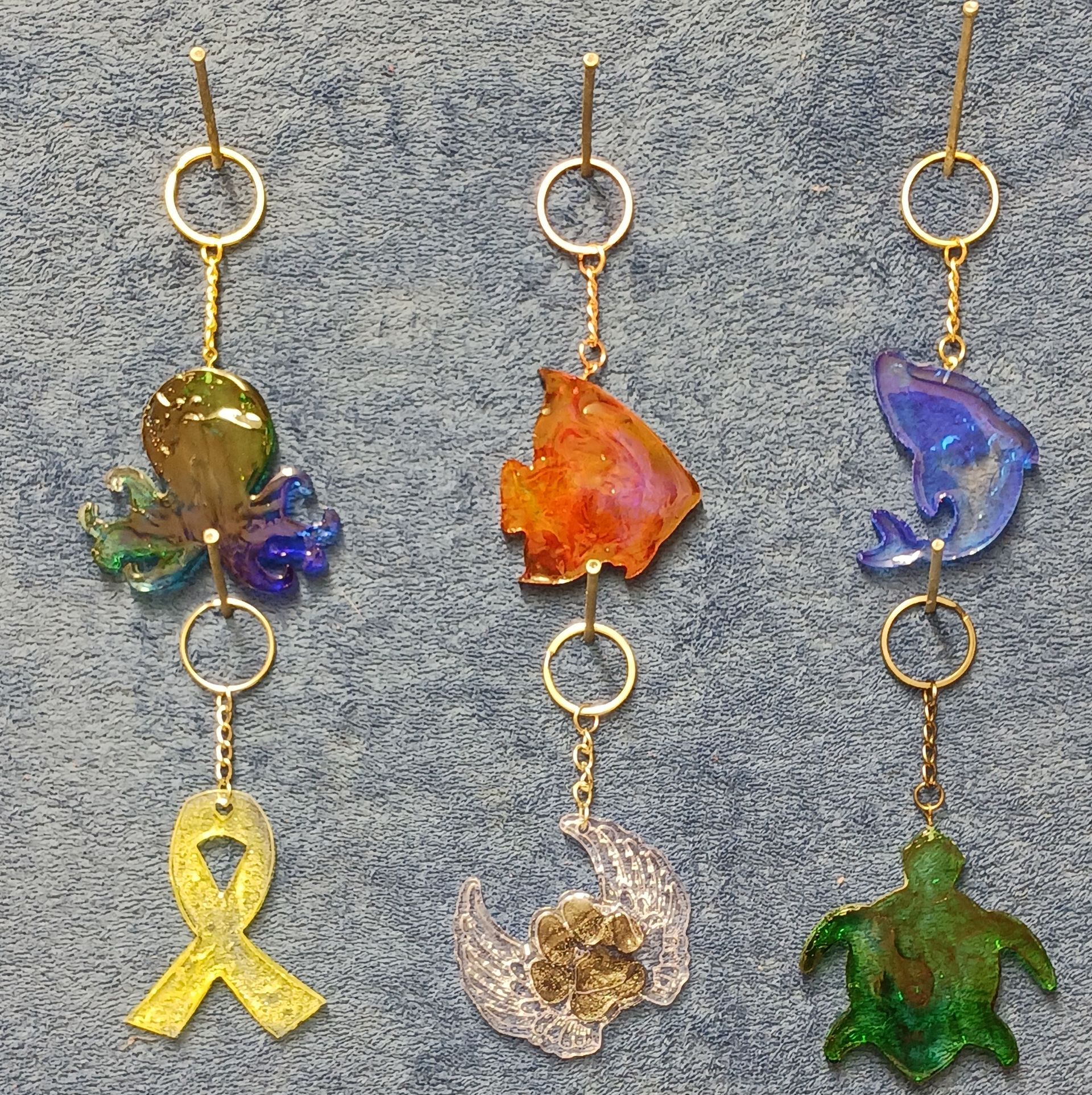 A group of keychains with a yellow ribbon a fish a turtle and a dolphin