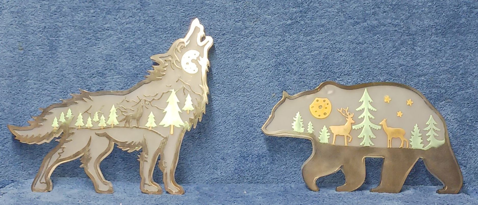 A resin wolf and a bear with trees and deer inside of them