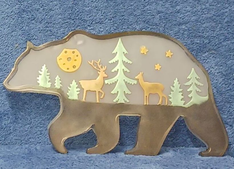 A silhouette of a bear with trees and deer on it