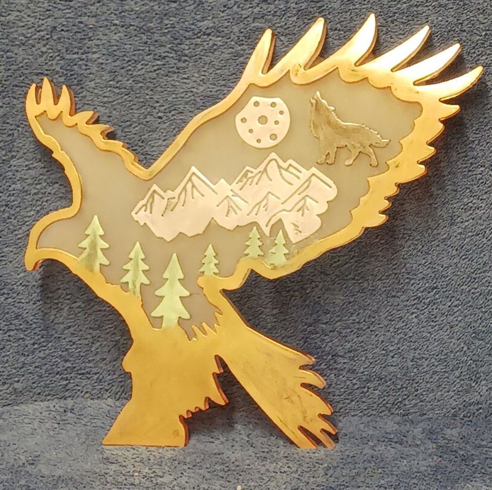 A wooden eagle with trees and mountains in the background