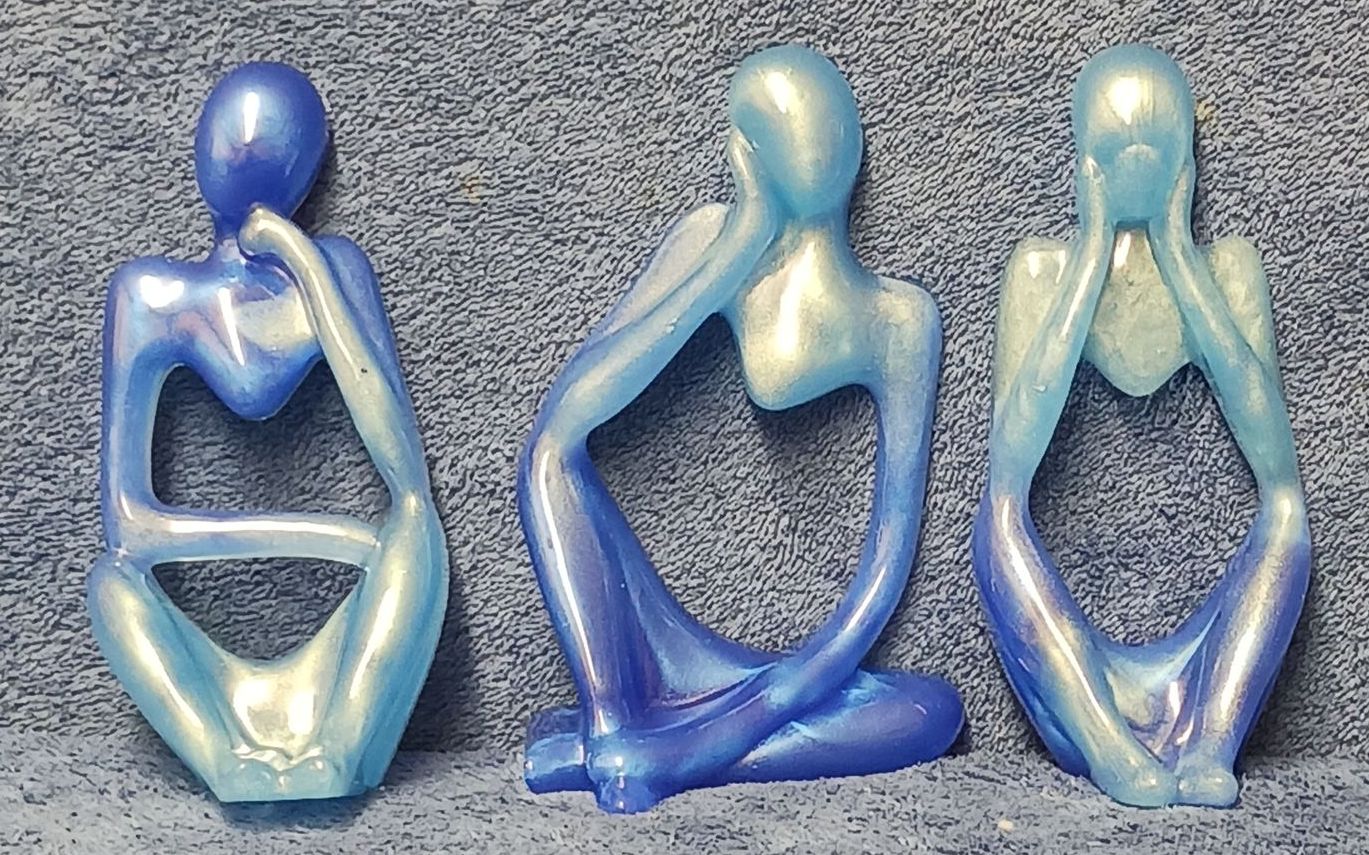 Three blue figurines are sitting next to each other on a table
