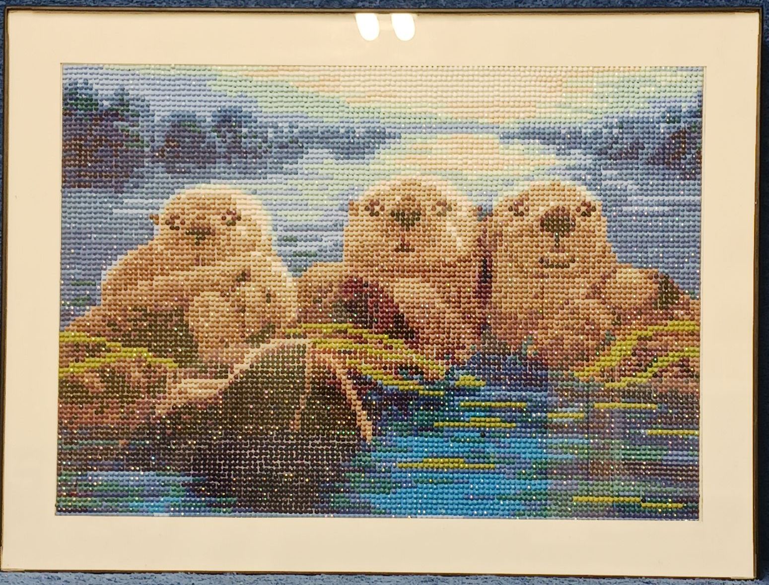 A diamond painting of four sea otters in the water