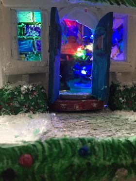 A gingerbread house with a blue door and stained glass windows.