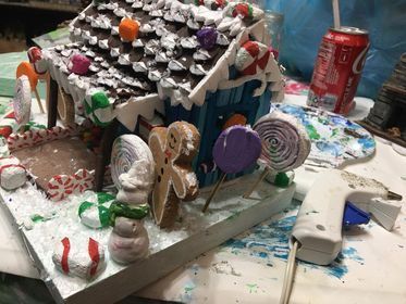 A gingerbread house is sitting on a table next to a can of coca cola.
