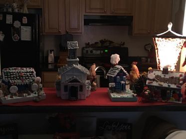 A row of gingerbread houses are sitting on a counter in a kitchen.