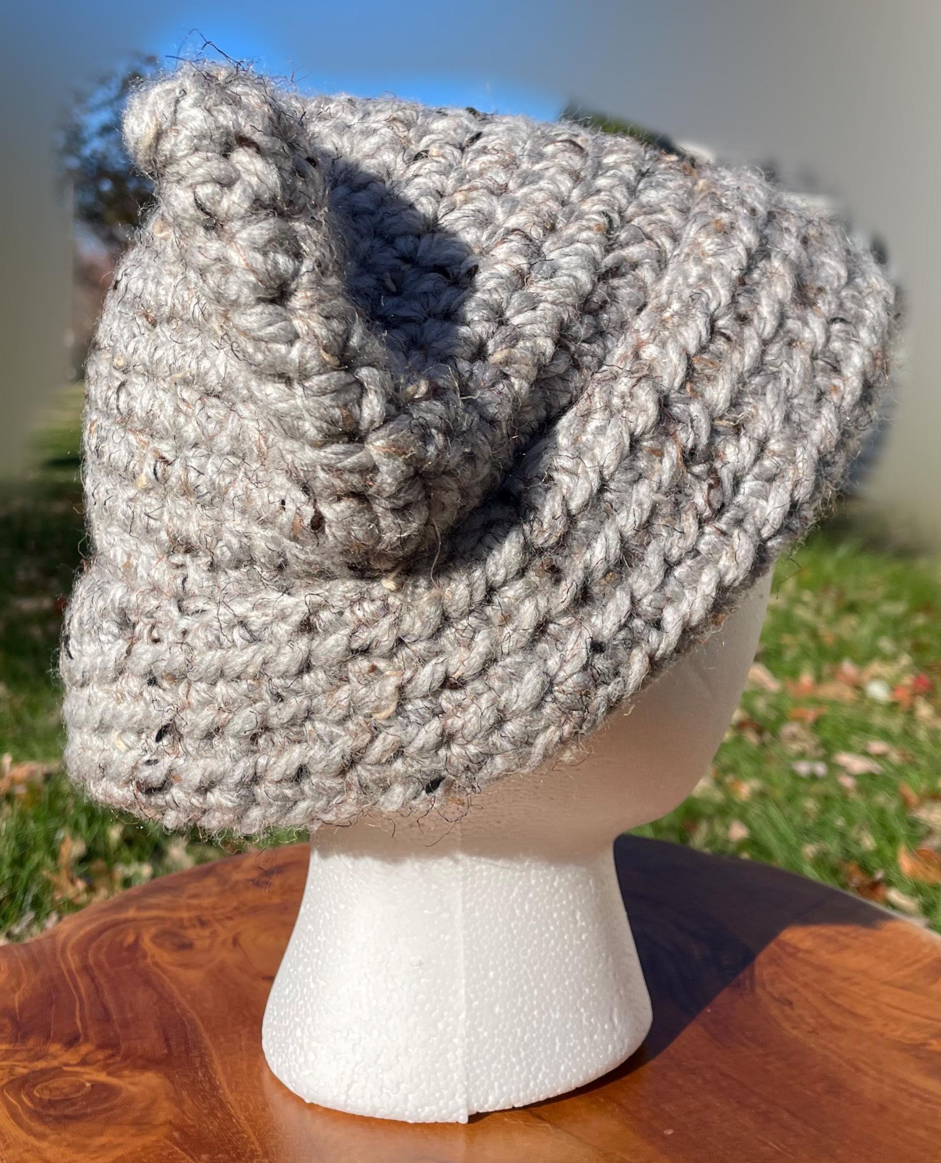 A crocheted hat is sitting on top of a wooden table.