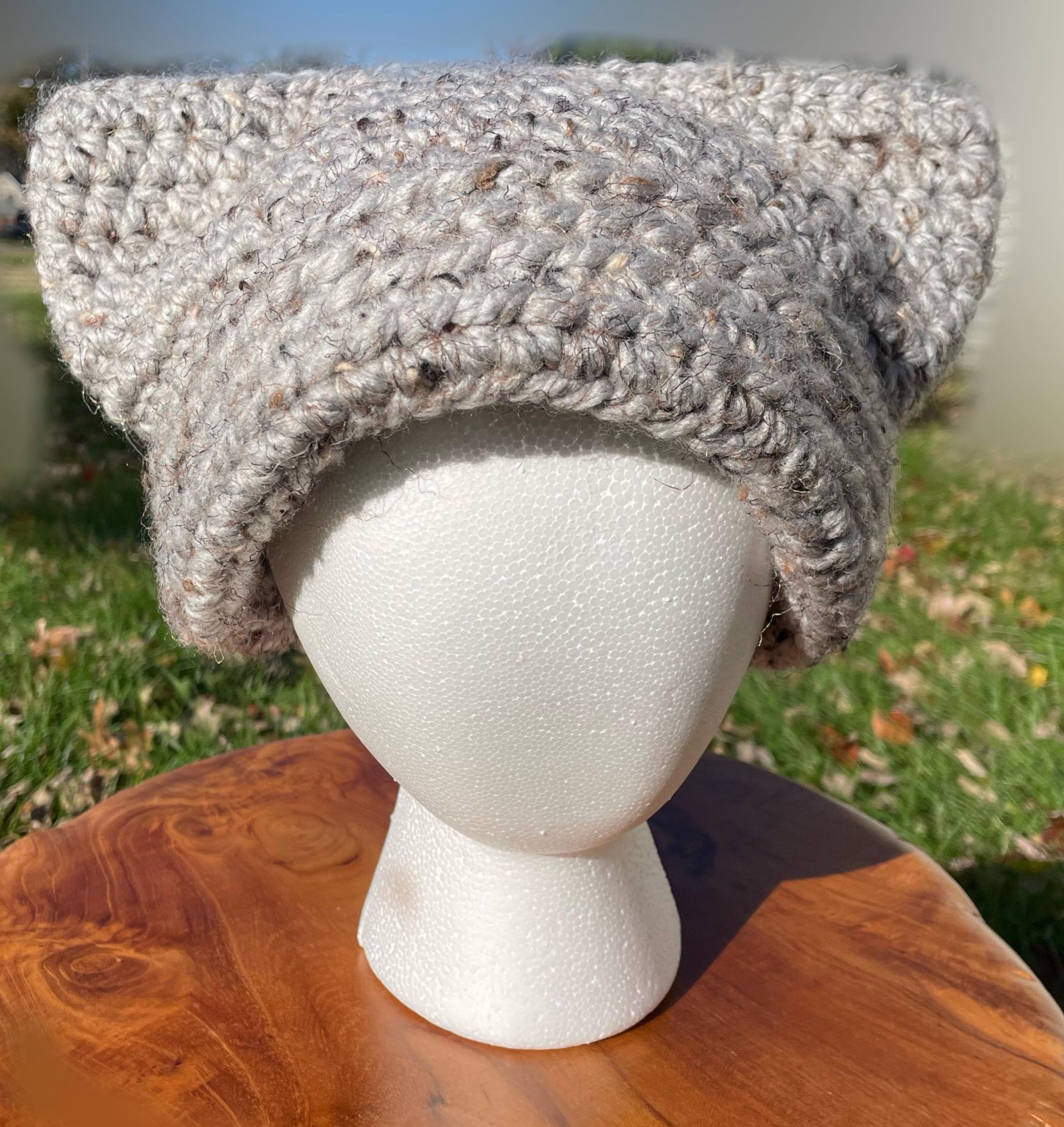 A crocheted hat with ears is on a mannequin head.
