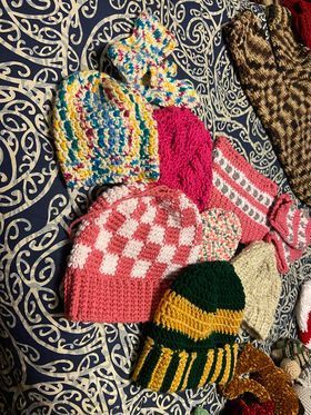 A bunch of crocheted hats are sitting on top of a bed.